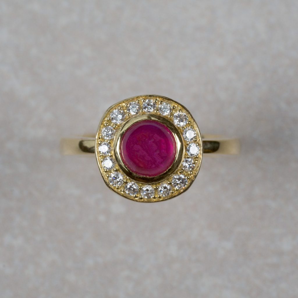 18 Carat Gold Ring set with a round Ruby Cabochon and 16 Round Briiliant Cut Diamonds.